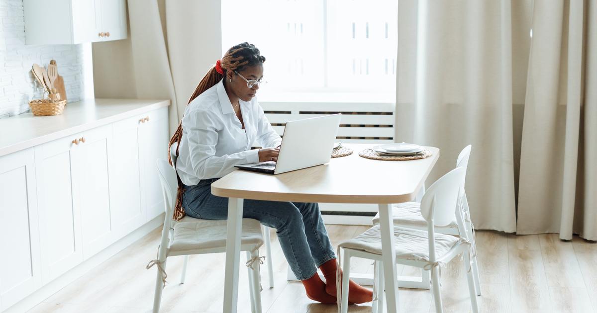 Writer sitting at table typing on a laptop