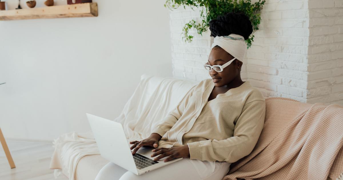 Writer sitting on couch typing on a laptop