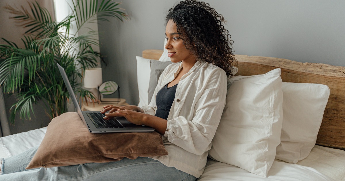 Writer sitting on a couch typing on a laptop