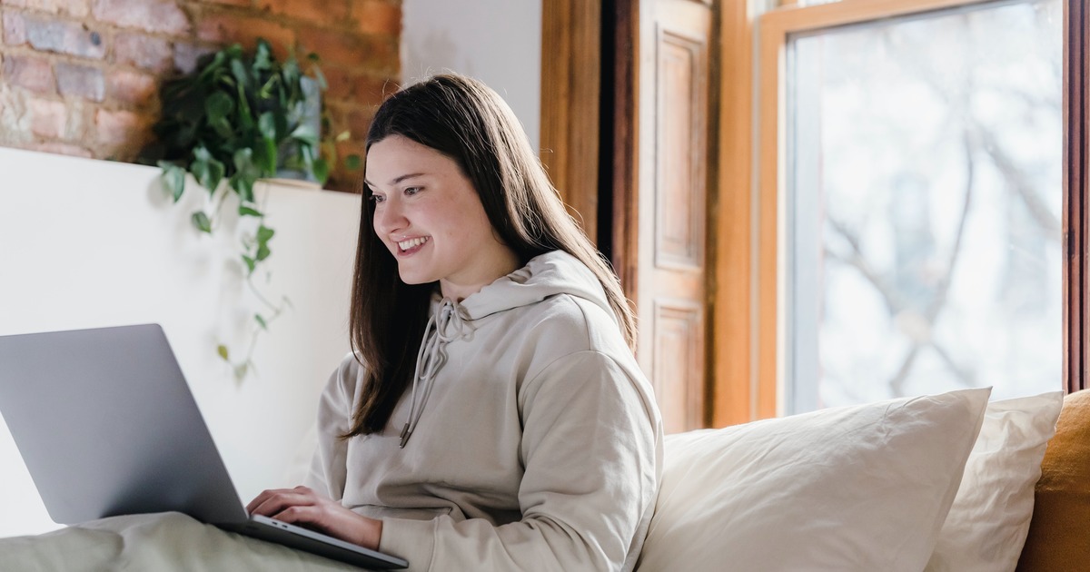 Writer sitting on couch typing on laptop