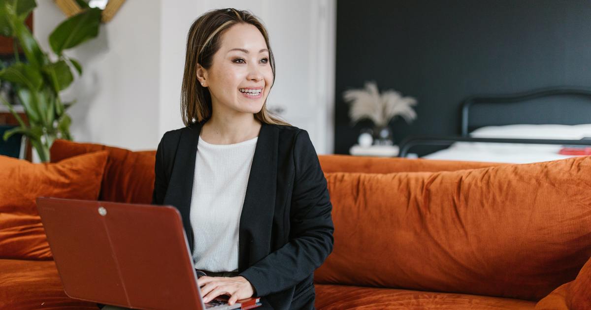 Woman smiling while typing on laptop