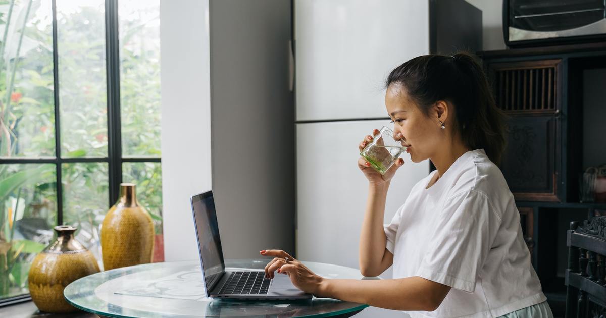 Writer typing on laptop while taking a sip of water