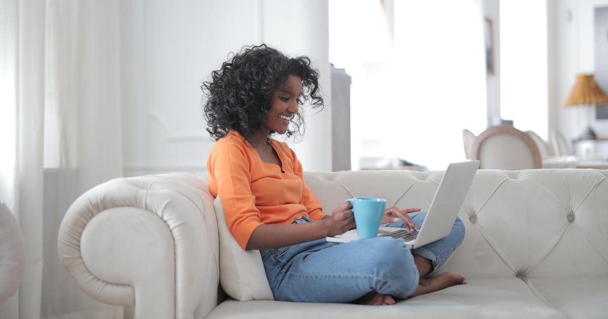 Writer sitting on couch with laptop and coffee