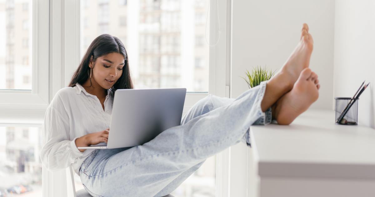 Writer typing on laptop with feet on table