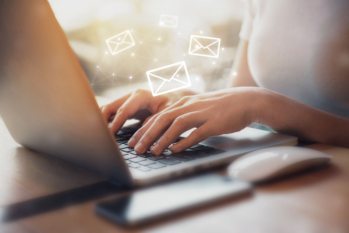 Woman’s hands typing on laptop superimposed with email symbols